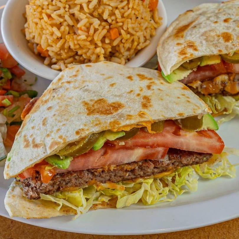 Stella's Diner quesadilla burger with lettuce, tomato, avocado, and jalapeños, served with rice.