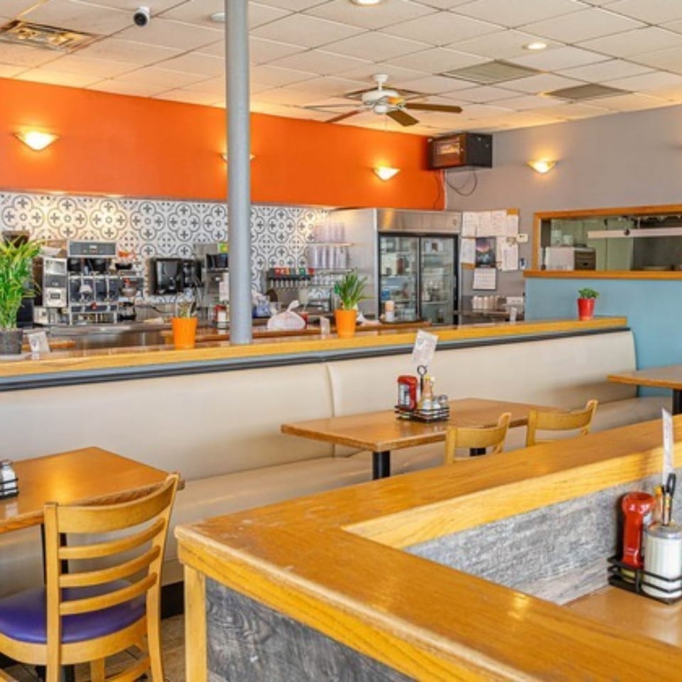 Interior of Stella's Diner with booths, tables, and a counter area with kitchen equipment.