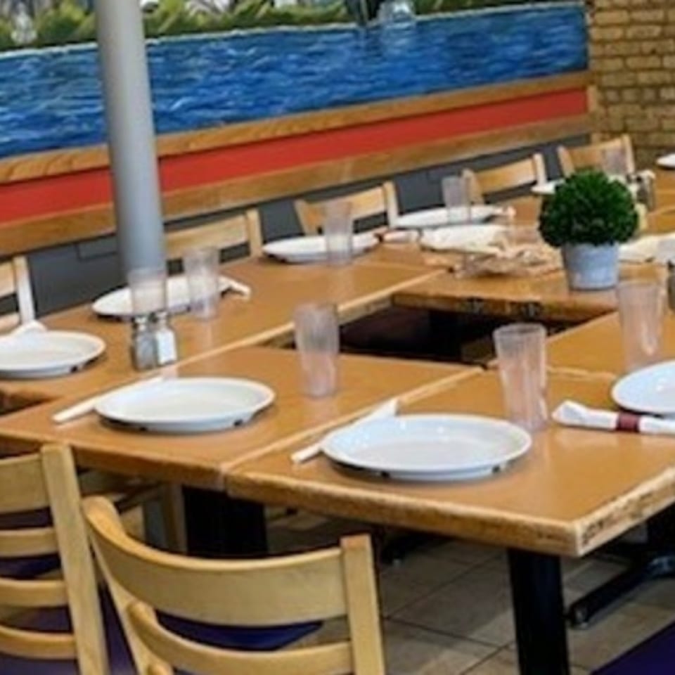 Long wooden tables with white plates, glasses, and salt and pepper shakers at Stella's Diner.